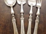 trois cuillères en argent et deux cuillères en argent posées sur une table en bois