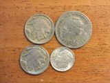 four different types of silver coins on a wooden surface