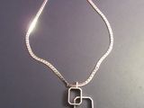 a silver necklace with a green stone hanging from it