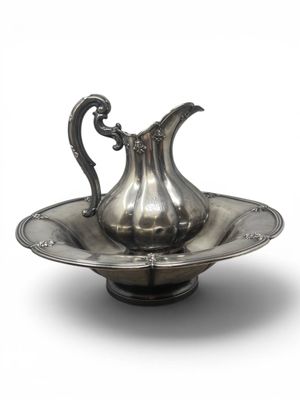 a silver pitcher on a silver plate on a white background
