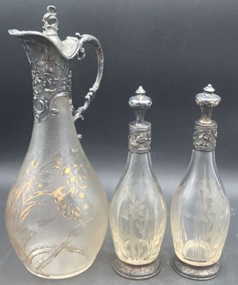 trois vases en verre et un pichet en métal argenté posés sur une table