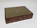 an old wooden box with a green cover on a white surface