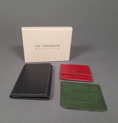 three different colored leather wallets sitting next to a white box