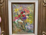 une personne tenant un tableau représentant des fleurs dans un cadre doré