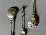 three silver spoons and a spoon with a handle and a spoon with a spoon on it