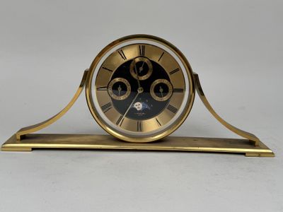 une horloge dorée avec un cadran noir sur un fond blanc
