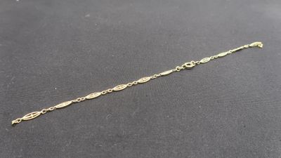 gros plan d'un bracelet en chaîne en or sur une surface noire