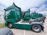 many green semi trucks parked in a parking lot