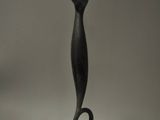 une sculpture noire posée sur une table, avec une photo en arrière-plan