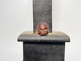 a statue of a skull sitting on top of a chair