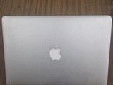 un ordinateur portable Apple posé sur une table au plateau en bois