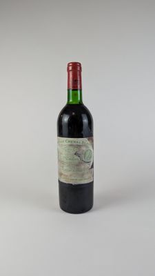 une vieille bouteille de vin posée sur une table blanche
