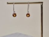 silver and citrine earrings on a gold stand with a white square