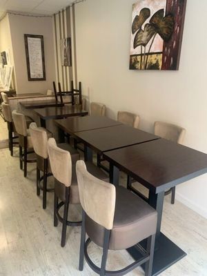 Des tables et des chaises sont alignées dans une pièce où est accroché un tableau au mur.