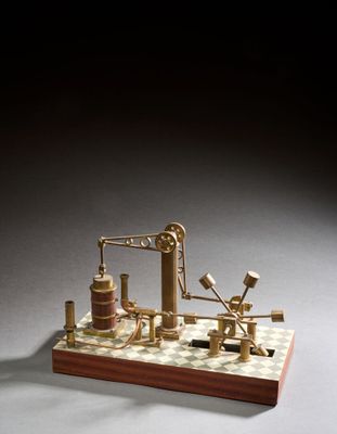 une image représentant une maquette miniature d'une machine à vapeur posée sur un damier