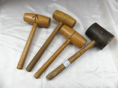 trois maillets en bois et un maillet posé sur un tissu blanc