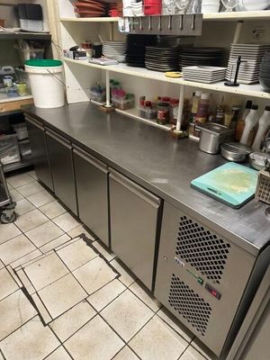 plan de travail en acier inoxydable dans une cuisine professionnelle, avec de nombreux plats disposés sur les étagères