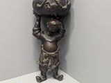 statue d'un garçon avec un sac sur la tête, dans un coin de la pièce