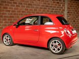 a small red car parked in front of a brick wall