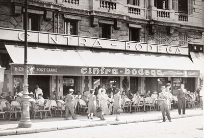 a black and white photo of a group of people outside of a store