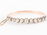 une bague en or rose ornée de cinq diamants, suspendue à une chaîne