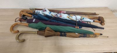 Plusieurs parapluies sont alignés sur une table en bois dans une pièce