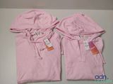 two pink hoodies with tags on them sitting on top of a table