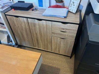 a desk with a printer and a file cabinet in the corner