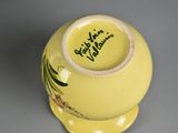 a yellow vase with a flower design on it