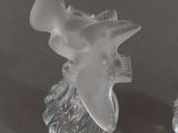two clear glass figurines of birds on a black surface