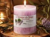 une bougie rose posée sur une table en bois, à côté de fleurs