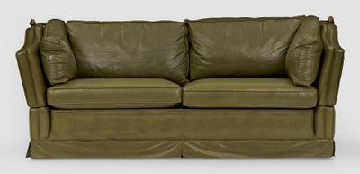 un canapé en cuir vert sur lequel sont posés deux coussins