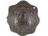 une image représentant une plaque métallique sur laquelle figure le portrait d'une femme