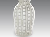 un vase blanc posé sur une table, sur fond gris