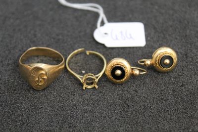 three gold rings with black stones and a tag on a table