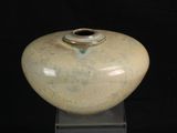 un vase posé sur un socle, sur un fond noir