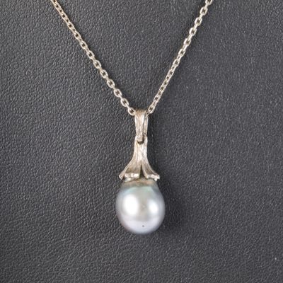 un pendentif en perles blanches et diamants sur une chaîne en argent