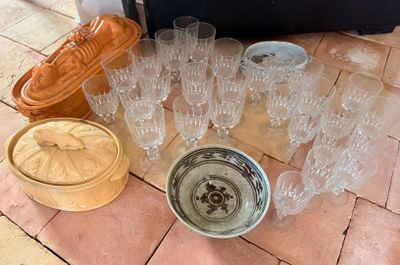 plusieurs verres et un bol posés par terre à côté d'une valise