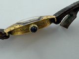a close up of a watch on a branch on a white surface