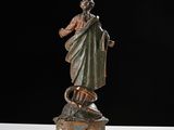 a statue of a woman holding a snake on top of a table