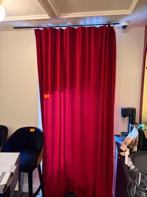 un rideau rouge dans un coin de la pièce, à côté d'un bureau