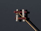 un gros plan d'une broche en diamant et rubis fixée sur une tige