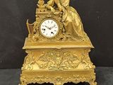 une horloge en or avec une femme assise dessus