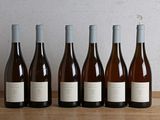 six bottles of wine are lined up on a wooden table