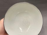 someone is holding a white bowl in their hand on a gray background