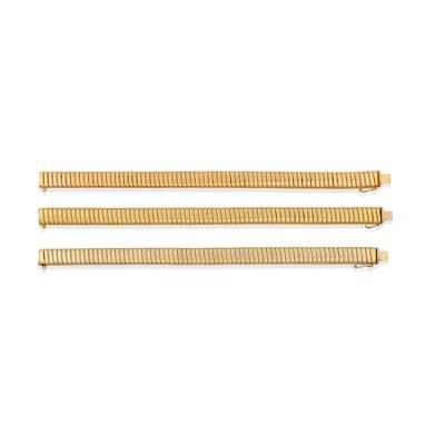 a set of three gold bracelets on a white background