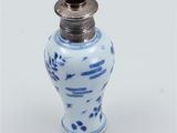 a small blue and white vase next to a silver spoon