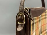 the brown and tan purse has a gold buckle on it