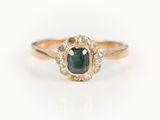 gros plan d'une bague en or avec un diamant vert et blanc