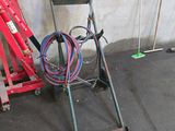 a red hand truck with a hose attached to the back of it